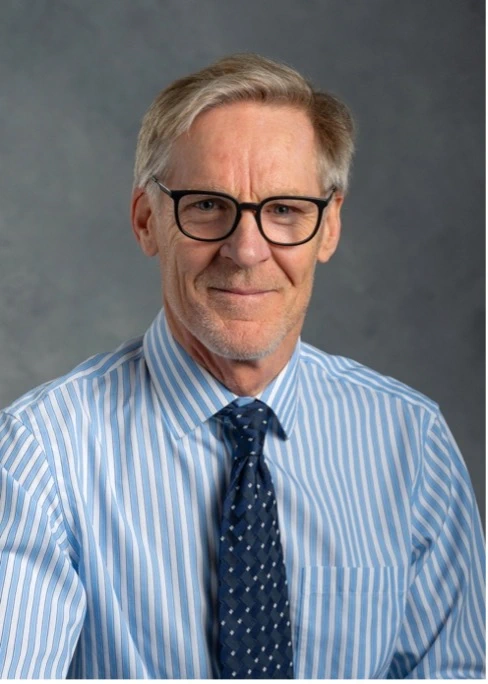 Portrait of Mat Reeves, professor in the Department of Epidemiology and Biostatistics, wearing black-rimmed glasses, a blue shirt with blue tie.